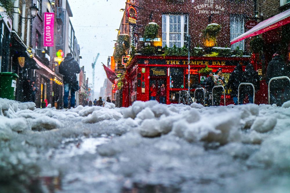 Der Pub The Temple Bar bei Schneefall, Bodenperspektive über schneebedecktes Kopfsteinpflaster