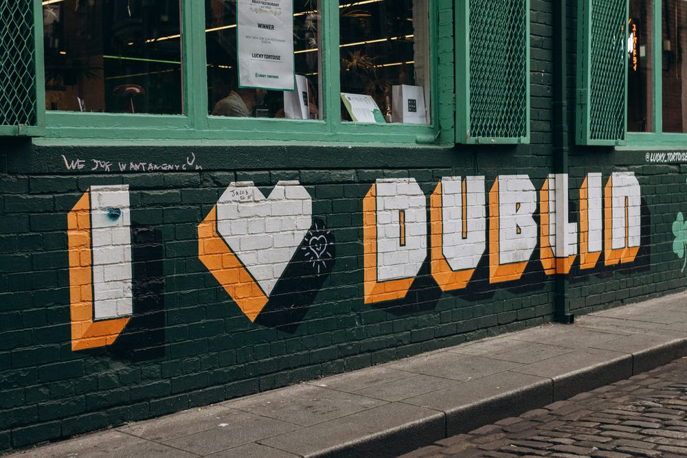Wandbild mit der Aufschrift „I love Dublin“ in Weiß und Orange auf dunkelgrüner Backsteinwand