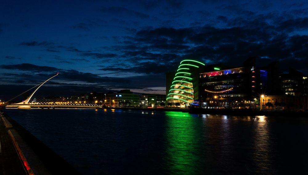 Die Samuel Beckett Bridge und das grün beleuchtete Convention Centre in den Dubliner Docklands zur blauen Stunde